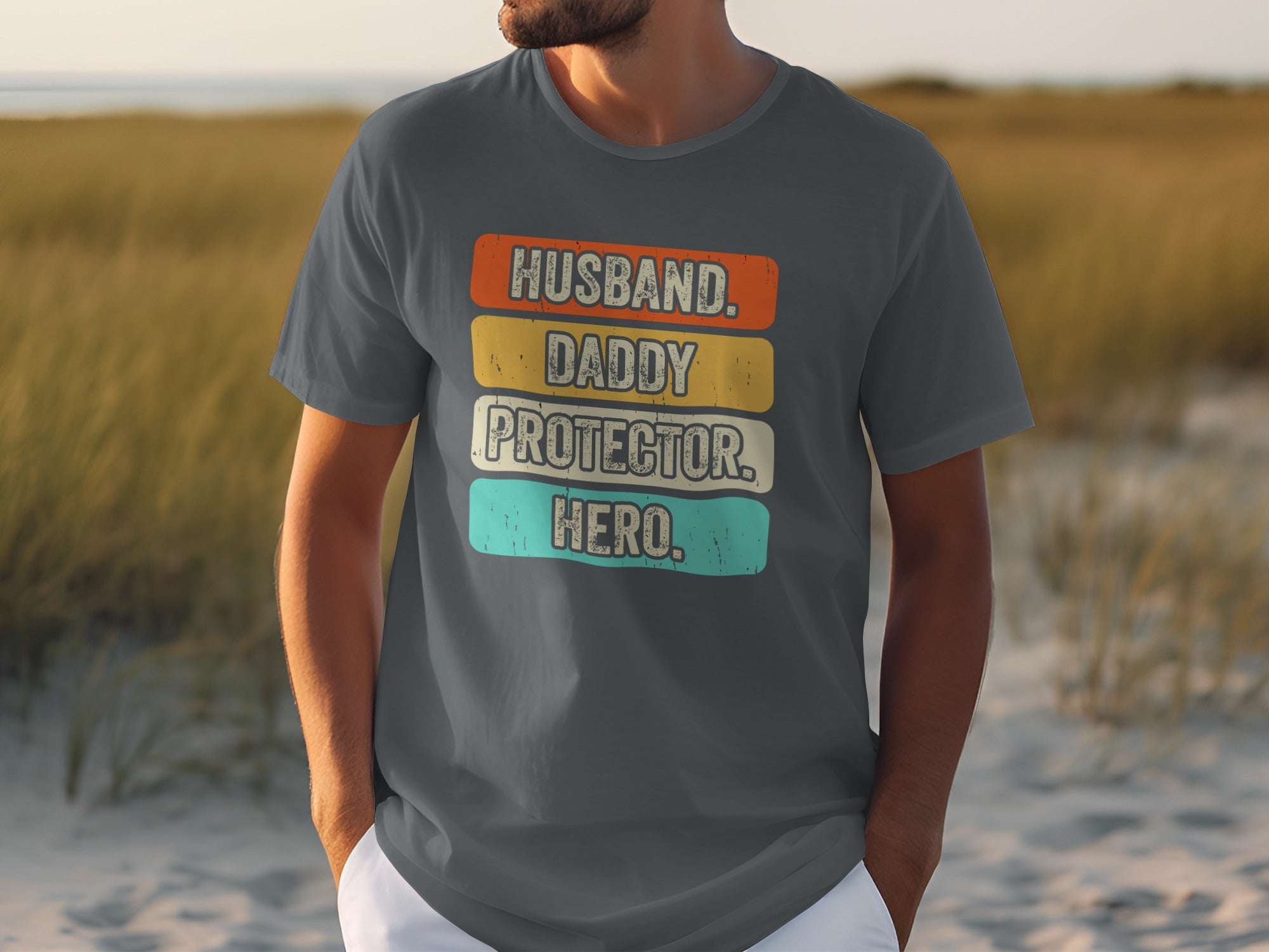 Dark grey t-shirt with text "Husband. Daddy. Protector. Hero." in colorful blocks.