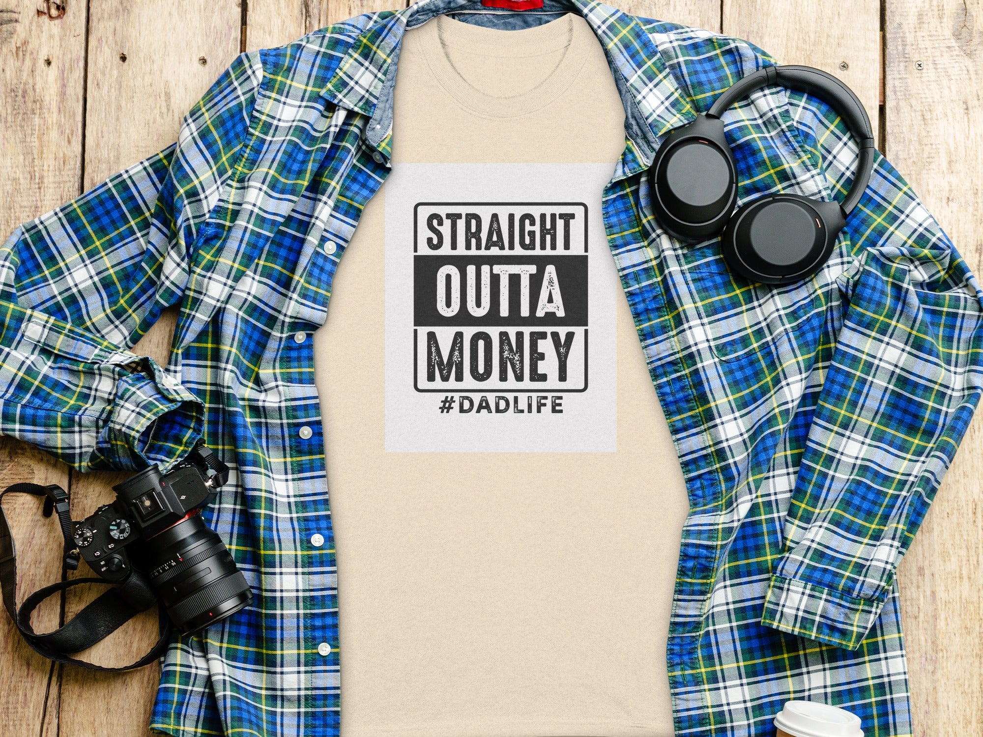 T-shirt with "STRAIGHT OUTTA MONEY #DADLIFE" graphic, plaid shirt, headphones, and camera.
