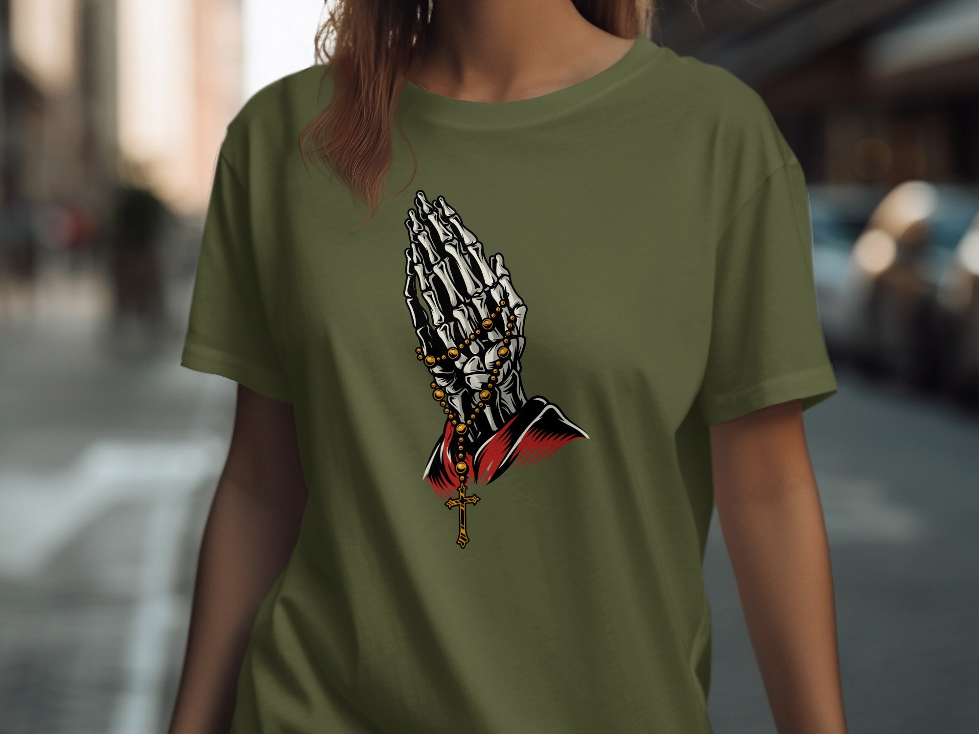 Skeleton hands praying with a rosary and crucifix on a green t-shirt.