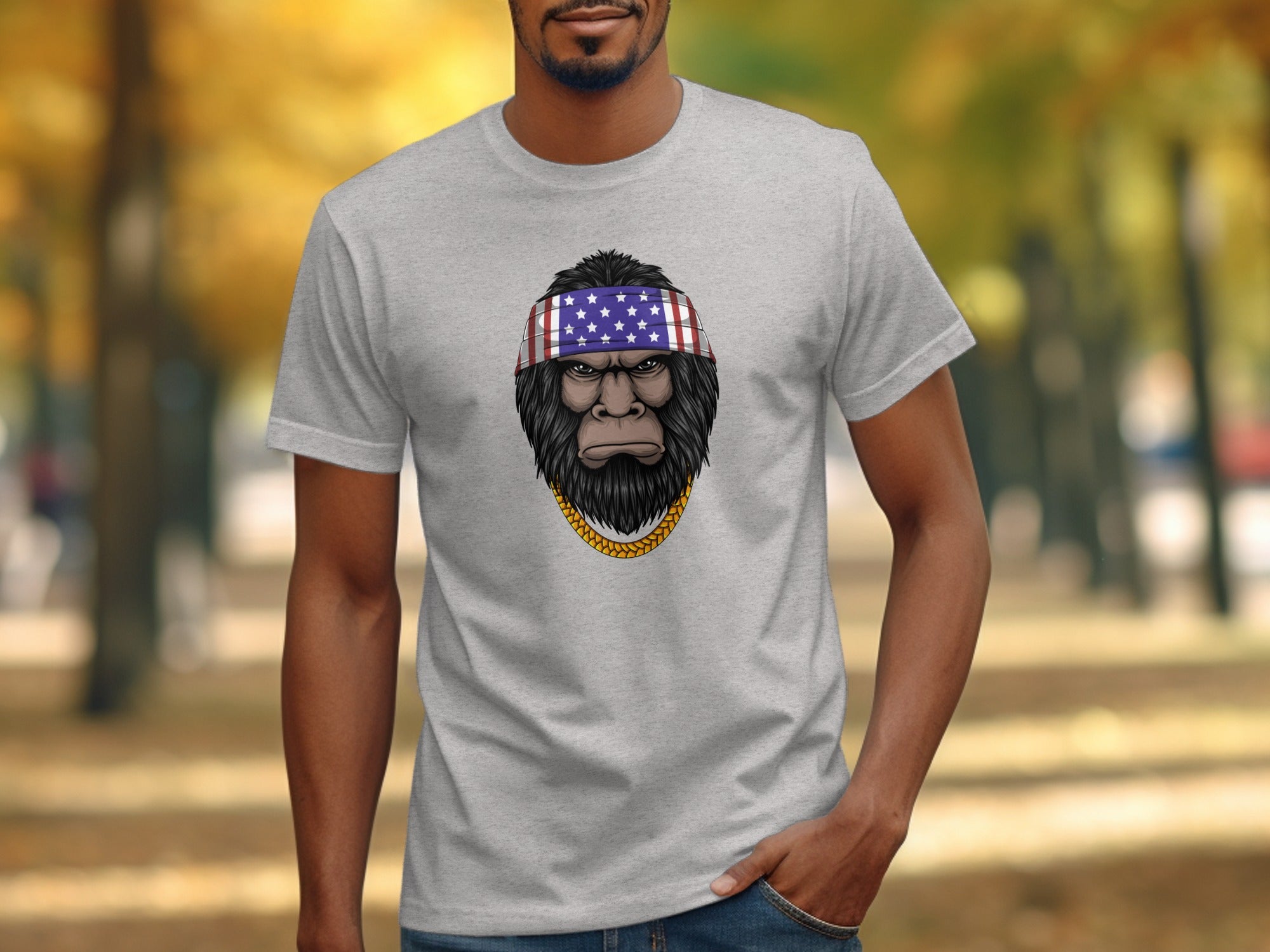 Bigfoot wearing American flag bandana and gold chain on grey t-shirt.