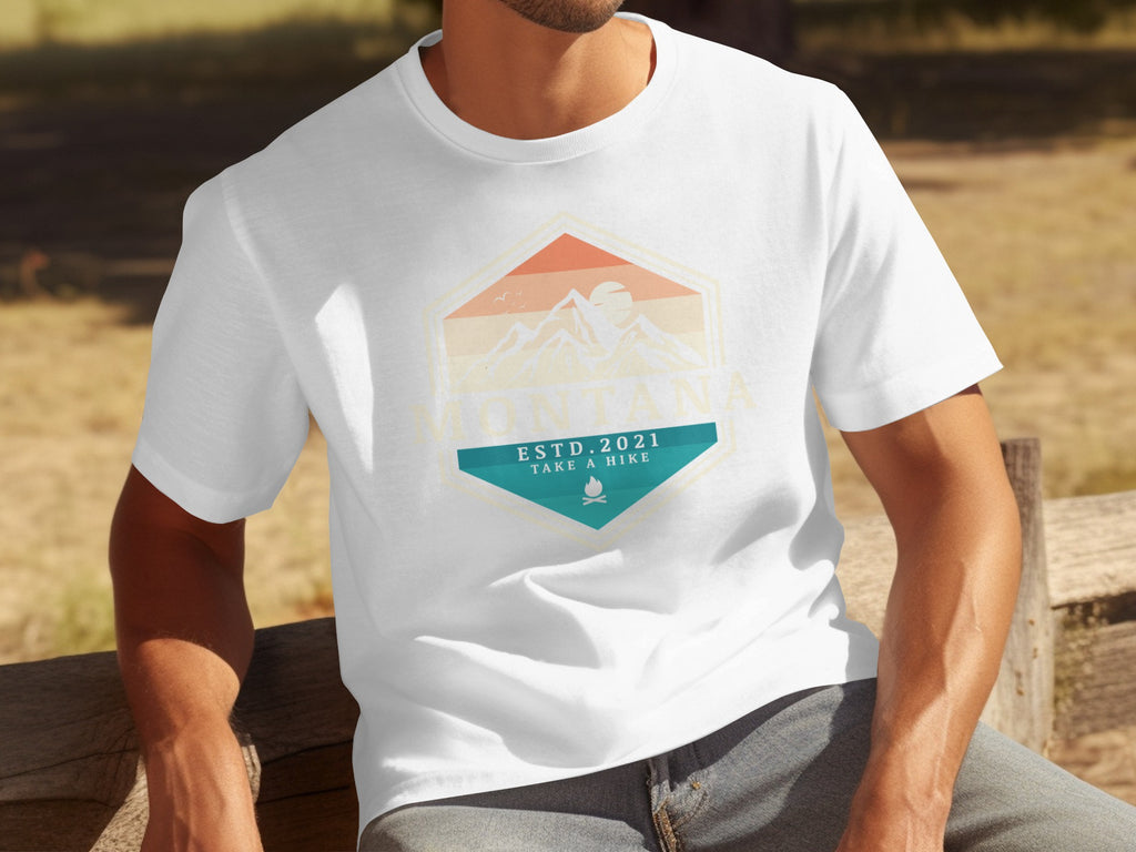 White t-shirt with vintage Montana mountains graphic, ESTD 2021, and campfire.