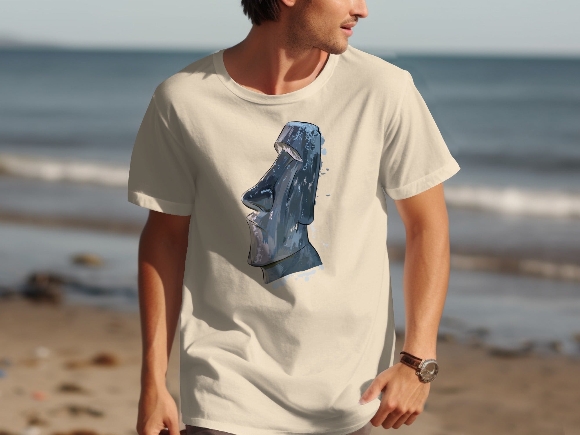 Cream t-shirt with a blue Moai statue graphic on a beach background.