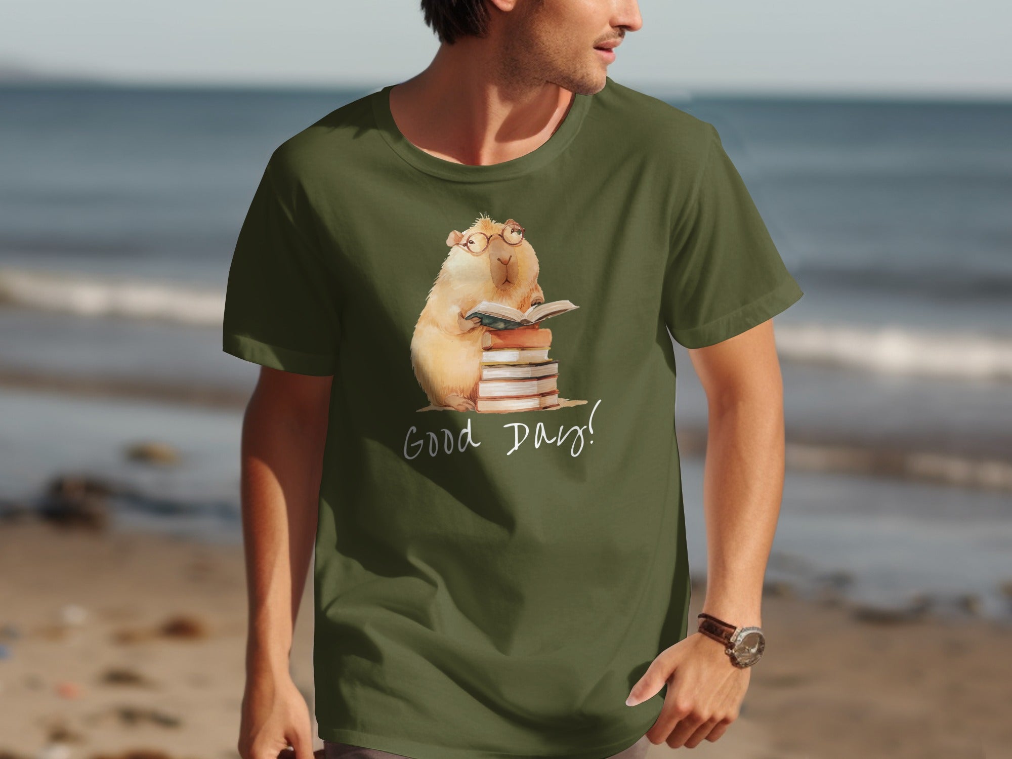 Green t-shirt with a watercolor capybara wearing glasses, reading on books, with text "Good Day!".