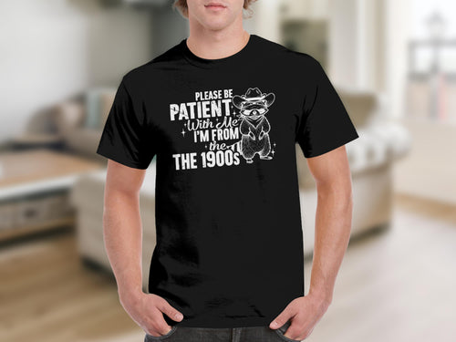 Black t-shirt with white text and raccoon graphic reading "Please be patient with me I'm from the 1900s".