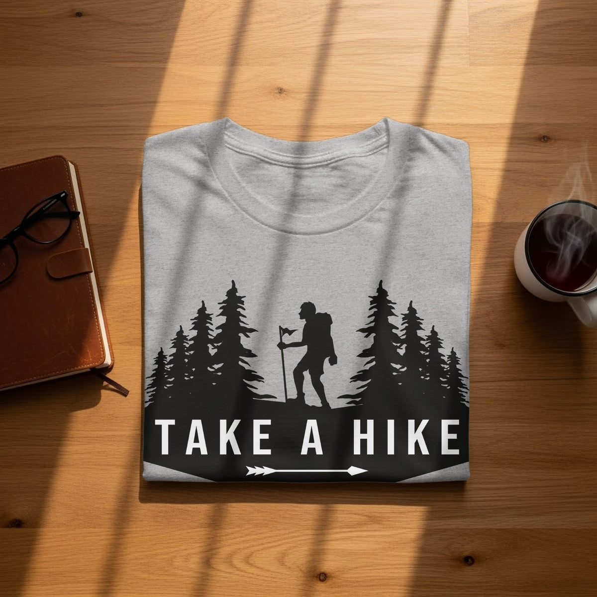 Gray t-shirt with a hiker and trees graphic that reads "TAKE A HIKE."