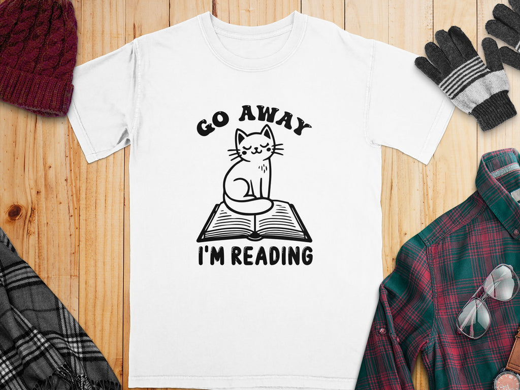 White t-shirt with black graphic of a cat on a book saying "GO AWAY I'M READING".