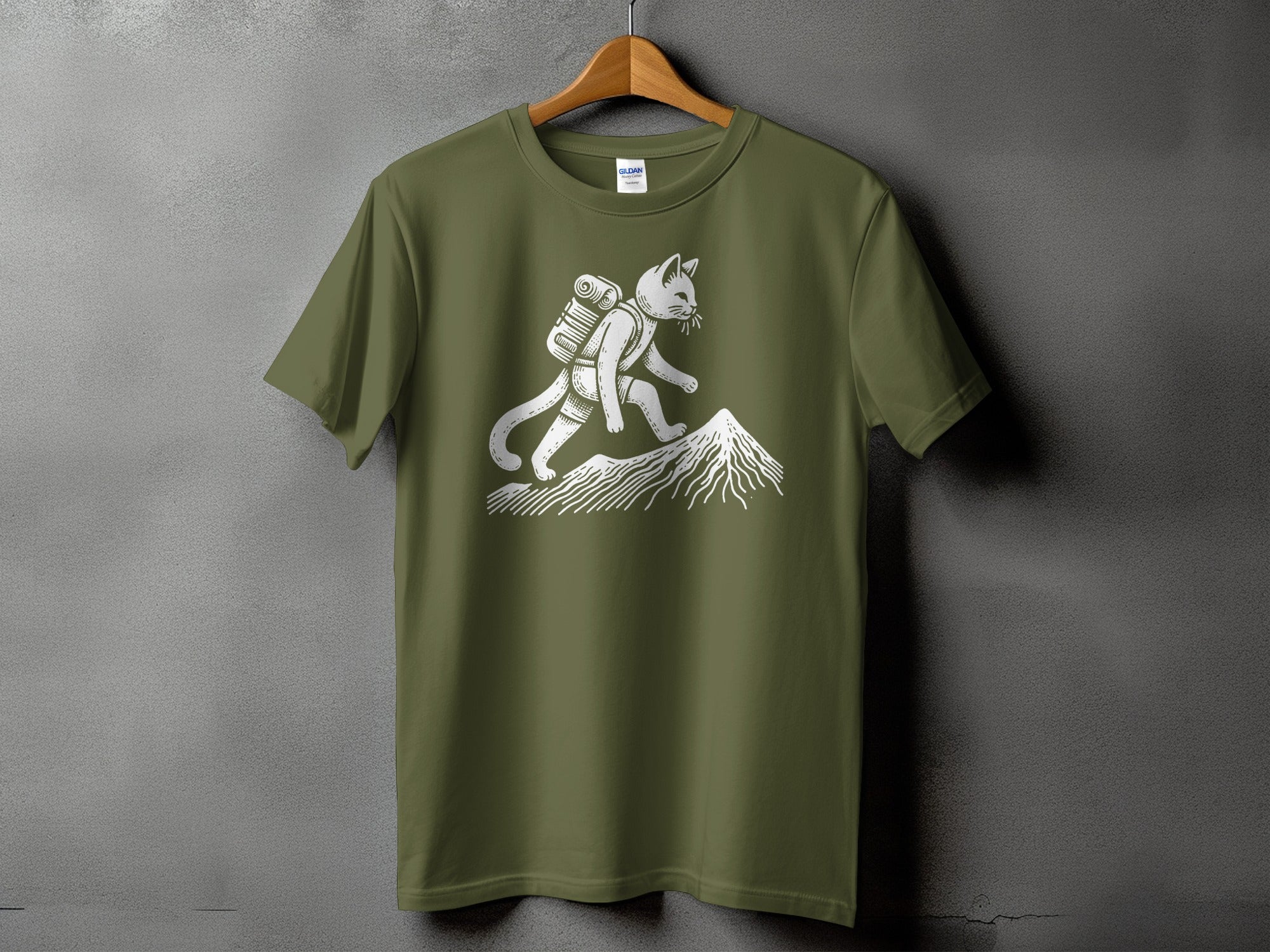 Green t-shirt with white graphic of a cat backpacking up a mountain.