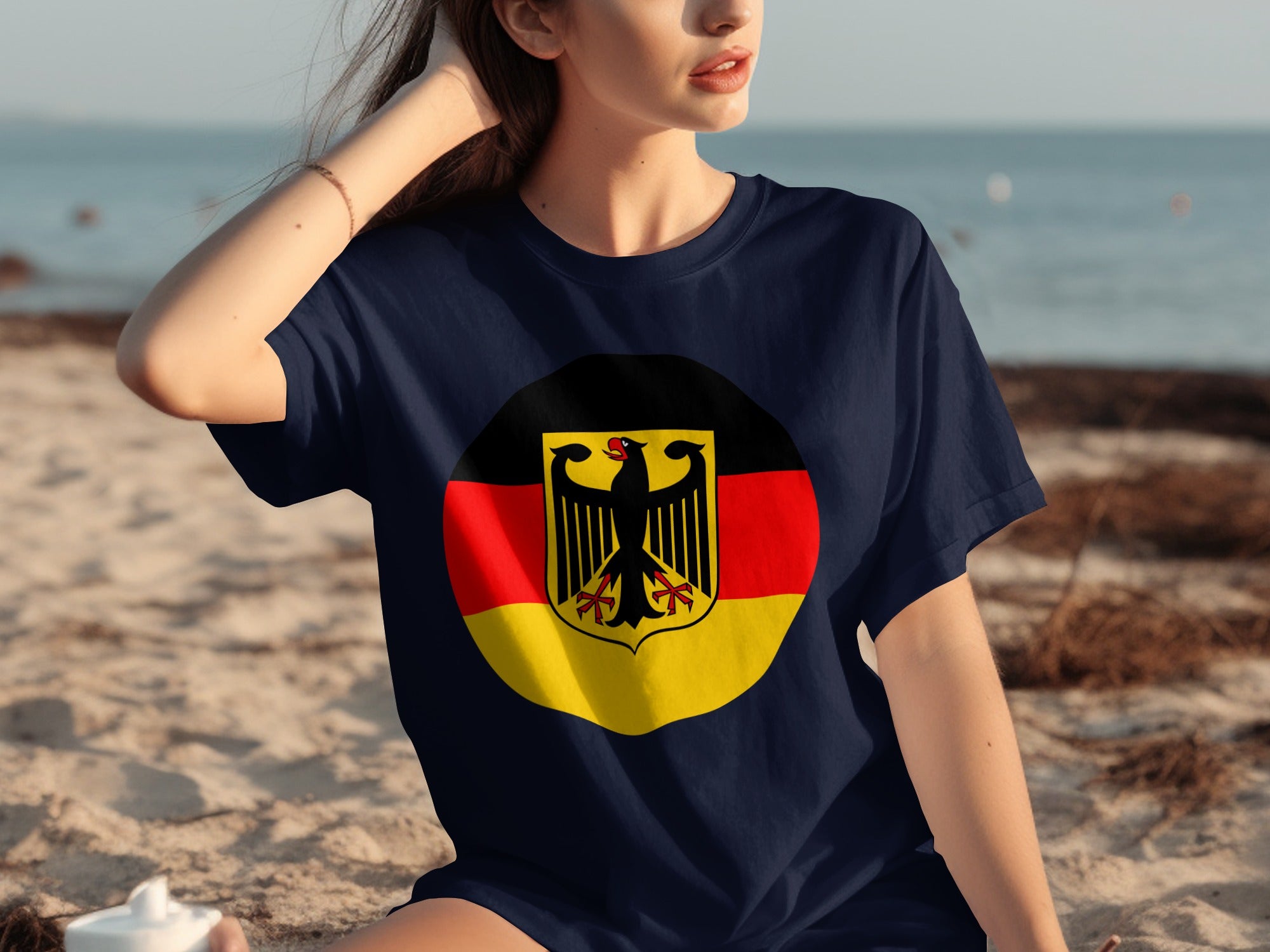 Dark blue t-shirt with German flag emblem on a beach.