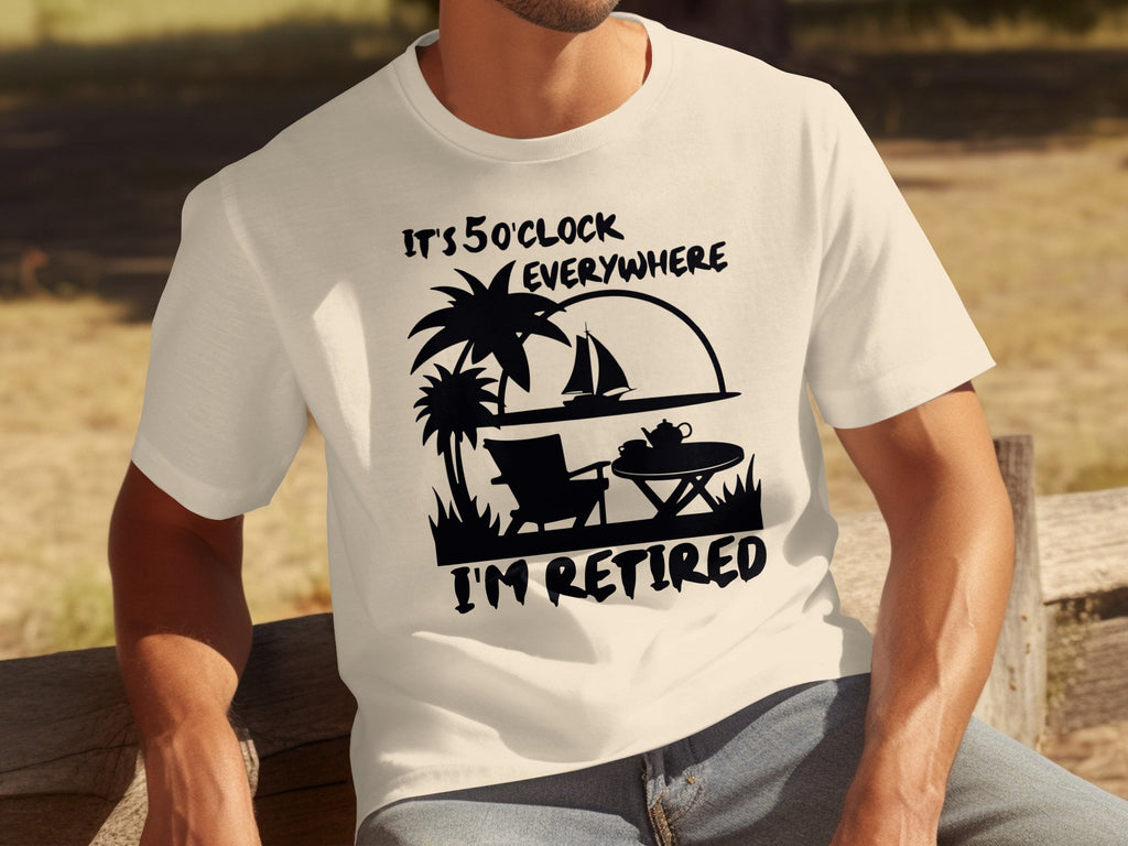 Cream t-shirt with black graphic of beach scene, palm trees, chair, table, sailboat, and text "IT'S 5 O'CLOCK EVERYWHERE I'M RETIRED".