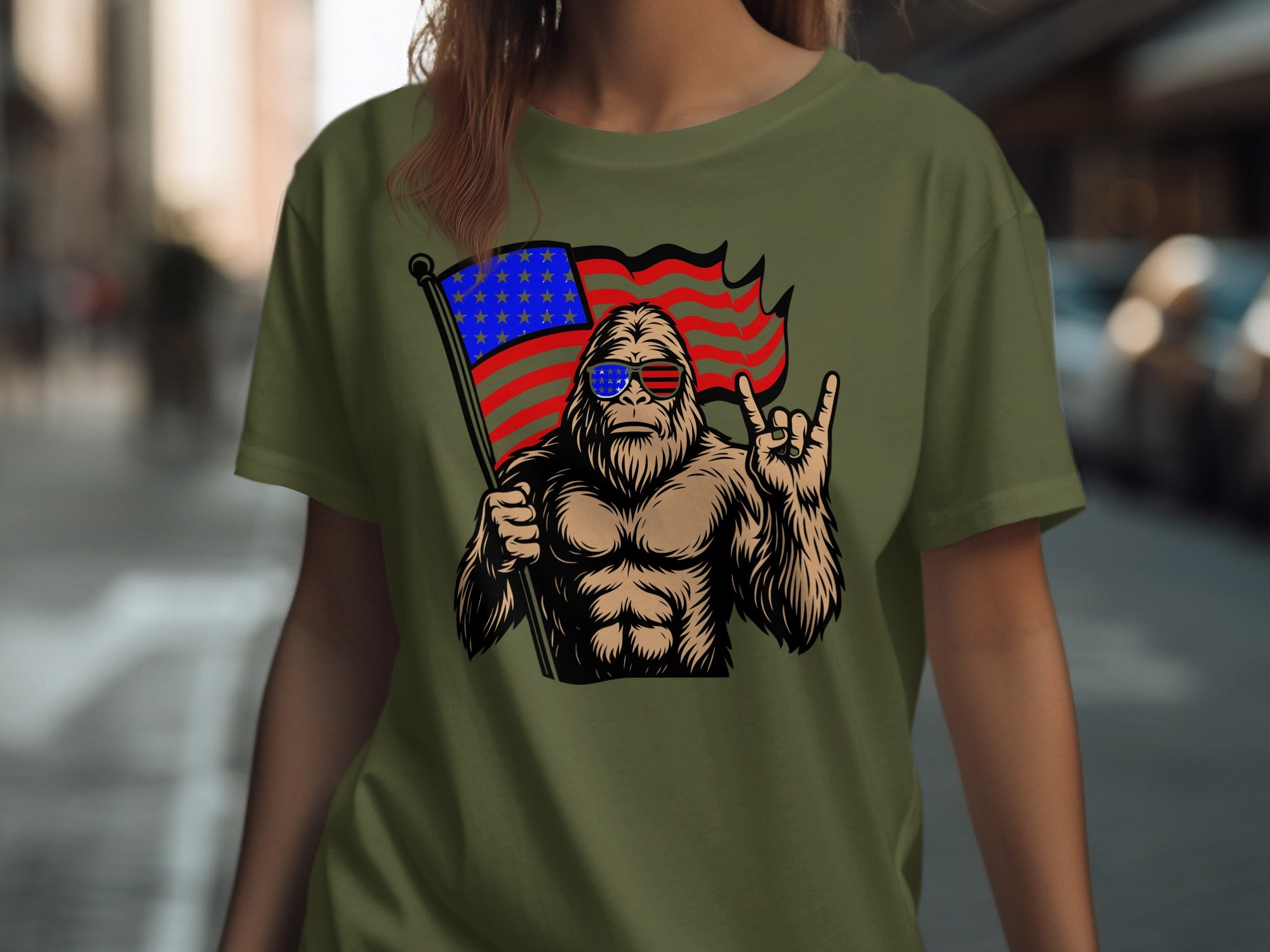 Bigfoot wearing sunglasses holds an American flag and gives the rock on hand gesture.