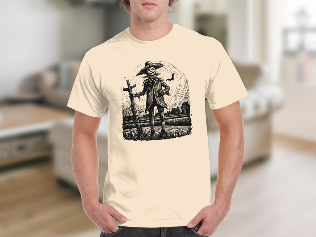 Black and white scarecrow with hat, cross, and raven graphic on a light yellow t-shirt.