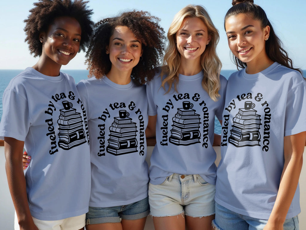 Four women smile wearing light blue t-shirts with a graphic of stacked books and text.