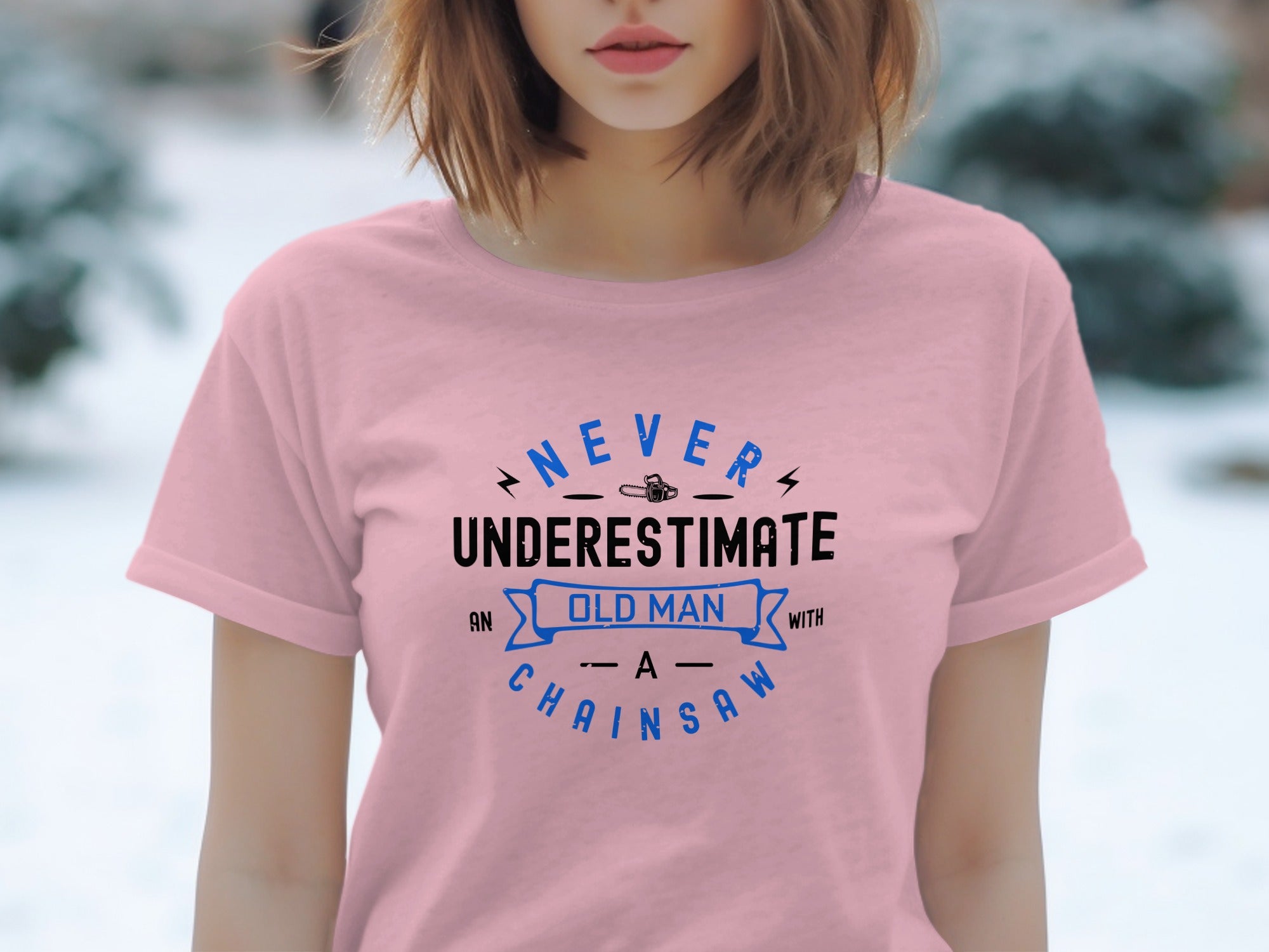 Pink t-shirt with text "NEVER UNDERESTIMATE AN OLD MAN WITH A CHAINSAW".