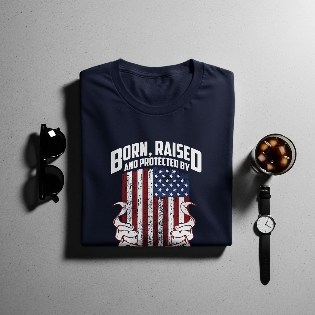 Navy t-shirt with "BORN, RAISED AND PROTECTED BY" above a distressed American flag design.