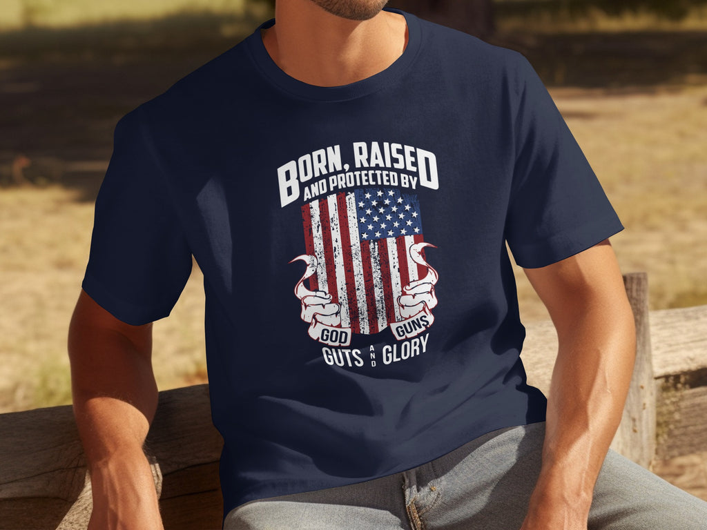 Dark blue t-shirt with distressed American flag and text: "Born, Raised, and Protected by God, Guts, Guns, and Glory."