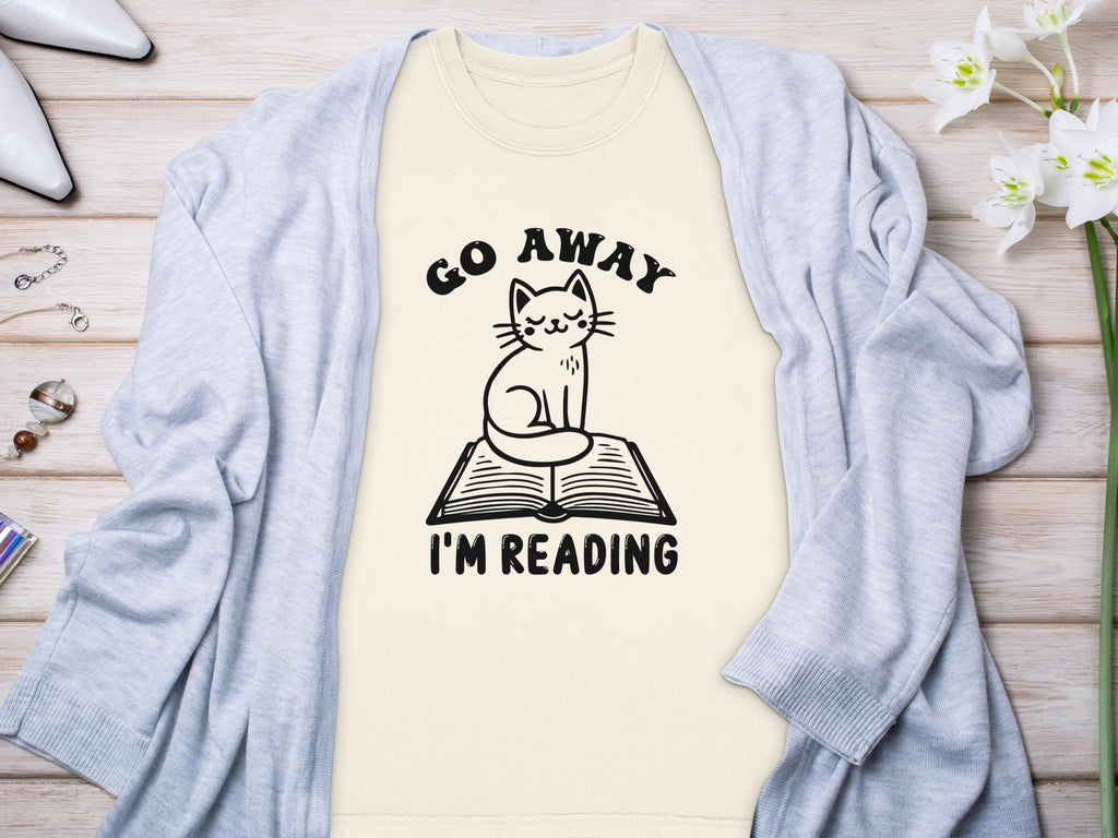 Light yellow t-shirt with cat on book graphic and "Go Away I'm Reading" text.