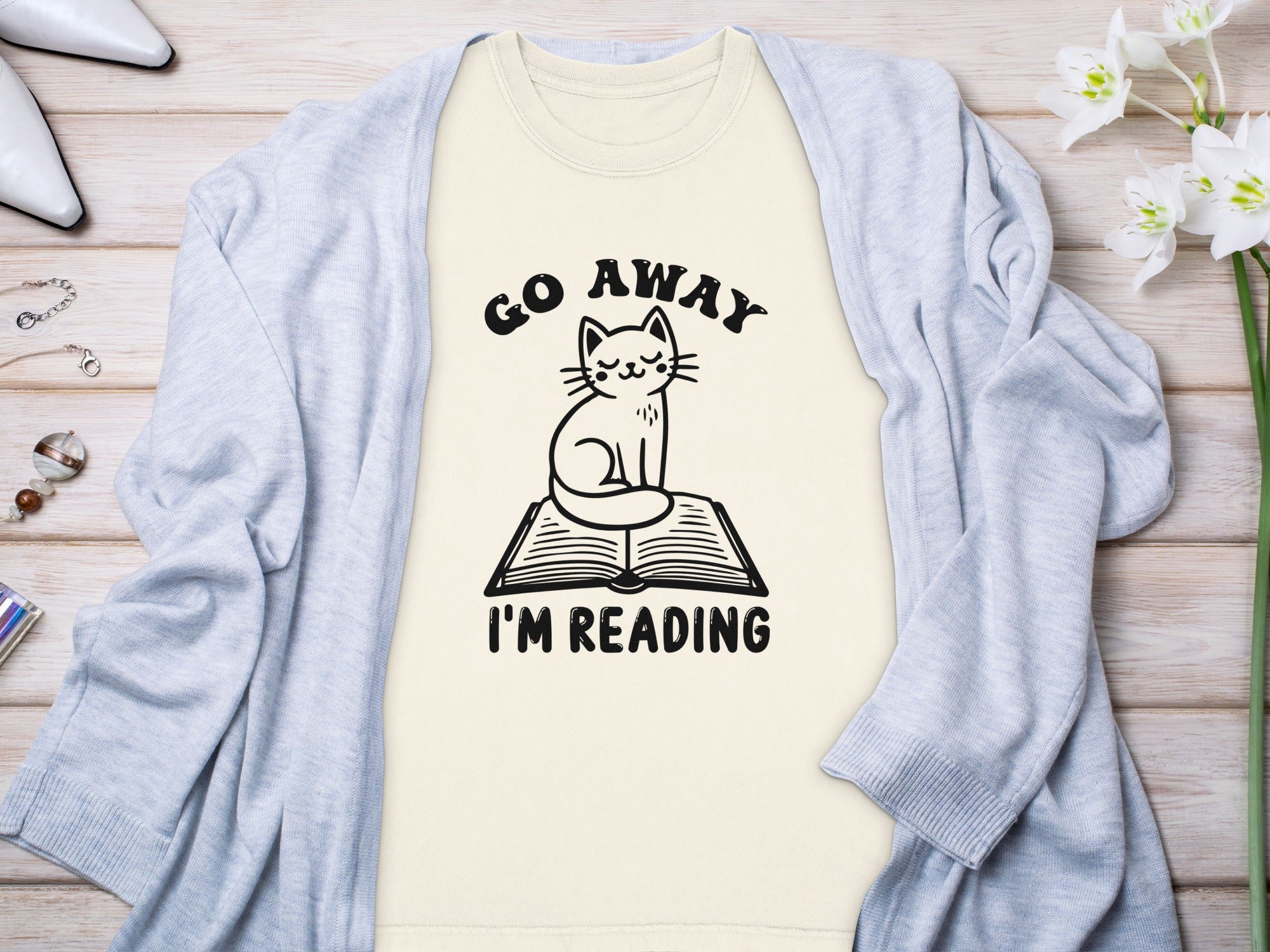 Light yellow t-shirt with cat on book graphic and "Go Away I'm Reading" text.