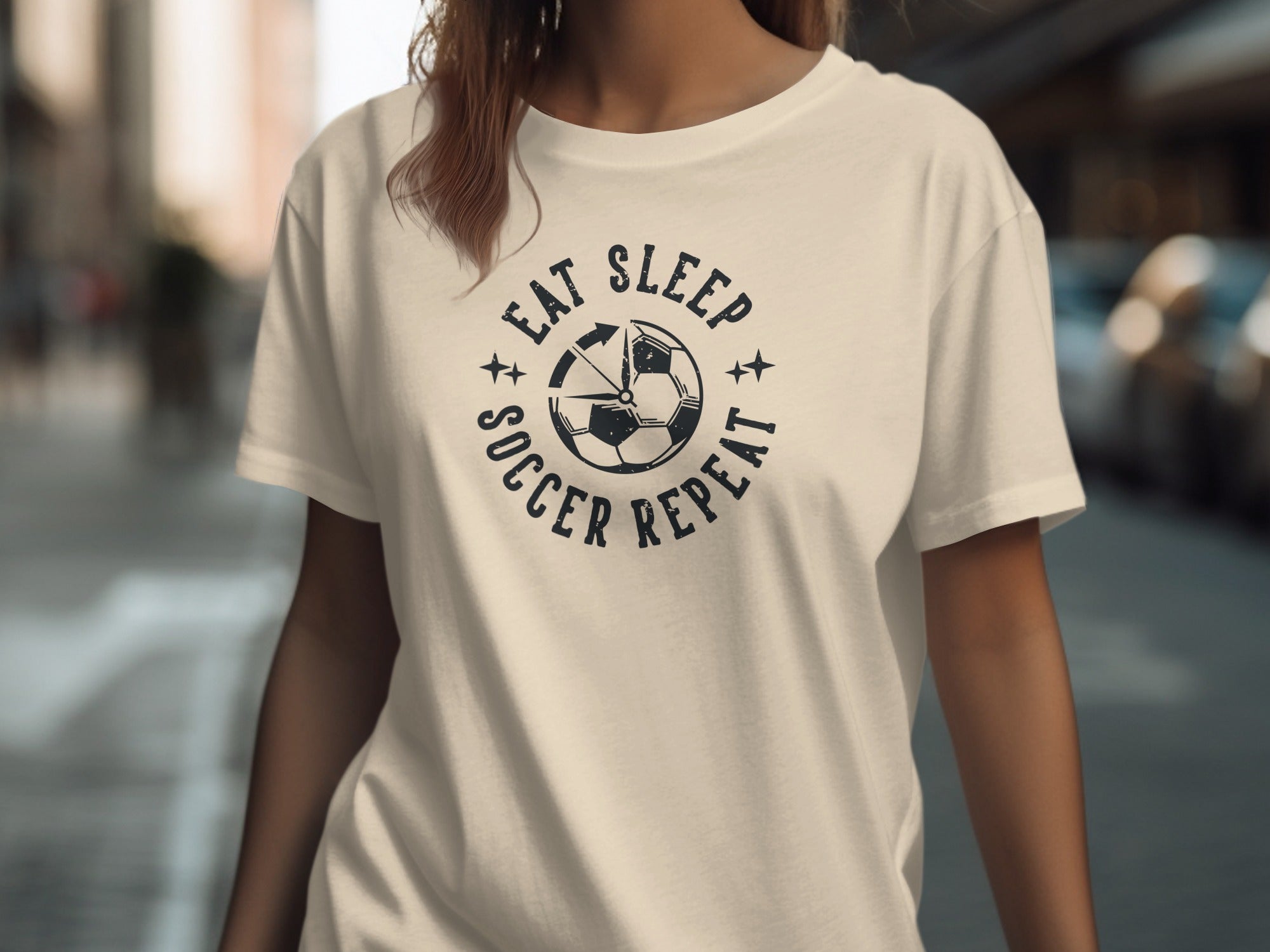 Cream t-shirt with black "Eat Sleep Soccer Repeat" graphic and soccer ball.