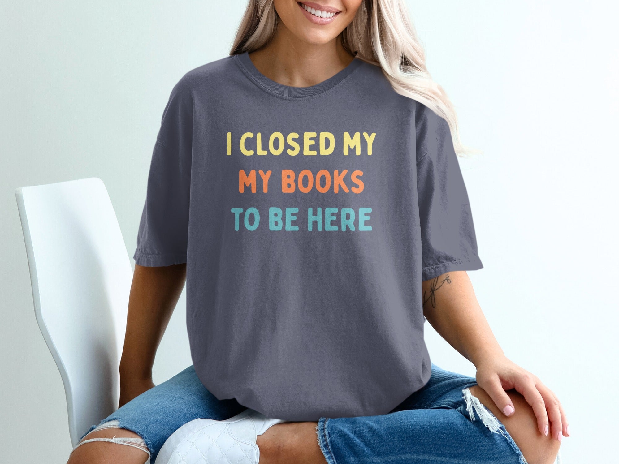 Dark grey t-shirt with yellow, orange, and teal text reading "I CLOSED MY MY BOOKS TO BE HERE".