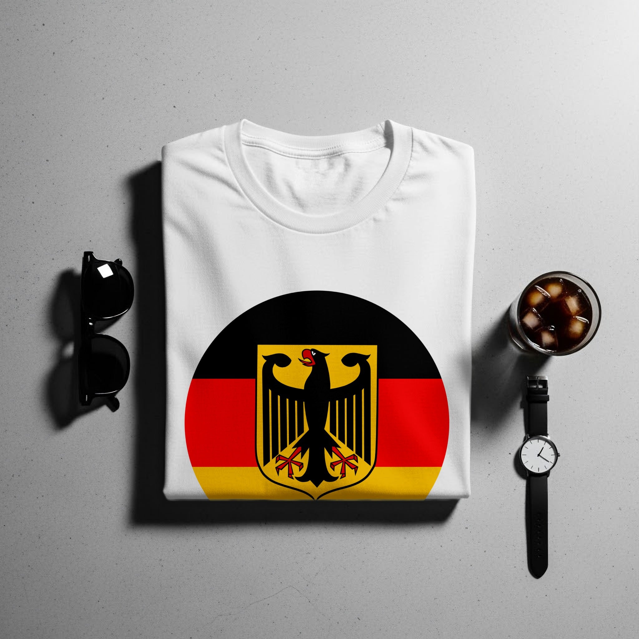 White t-shirt with German flag emblem, sunglasses, watch, and drink.