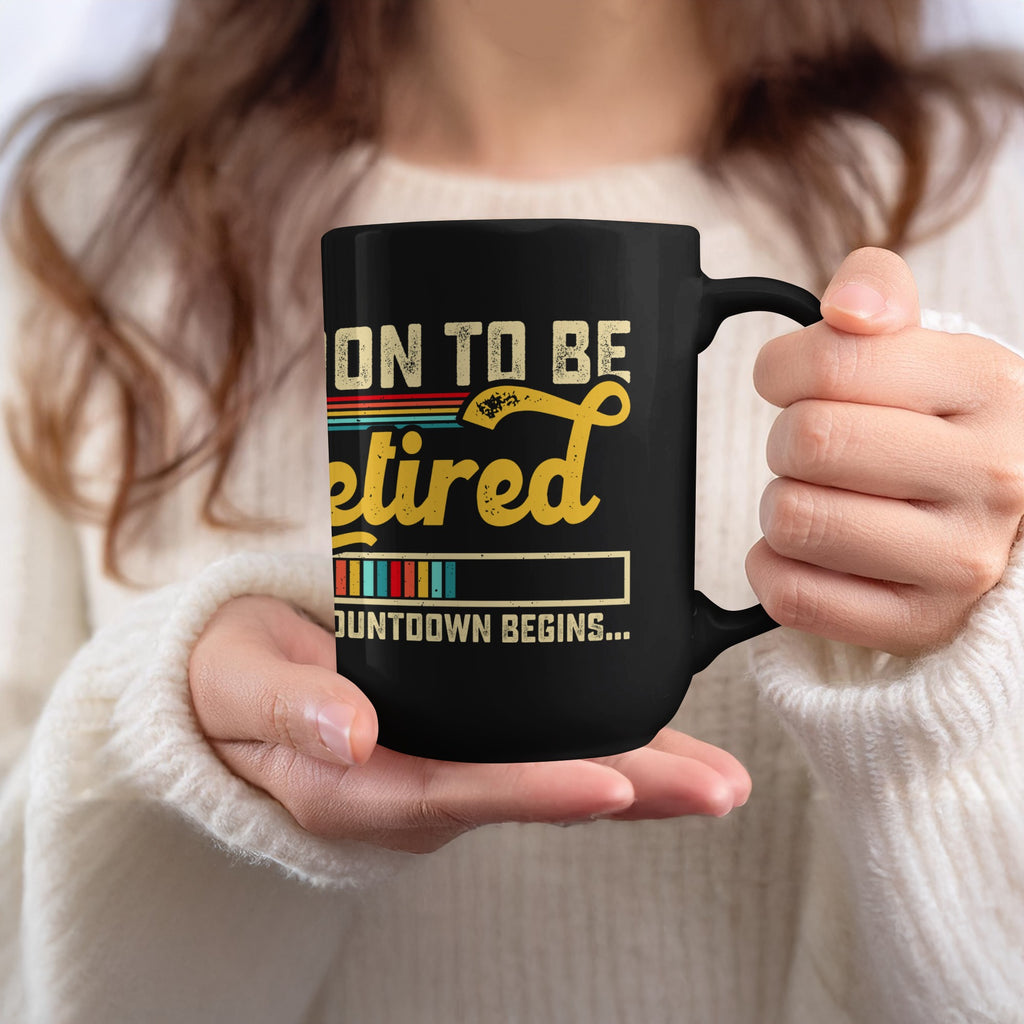 Black mug with text "ON TO BE RETIRED COUNTDOWN BEGINS..."