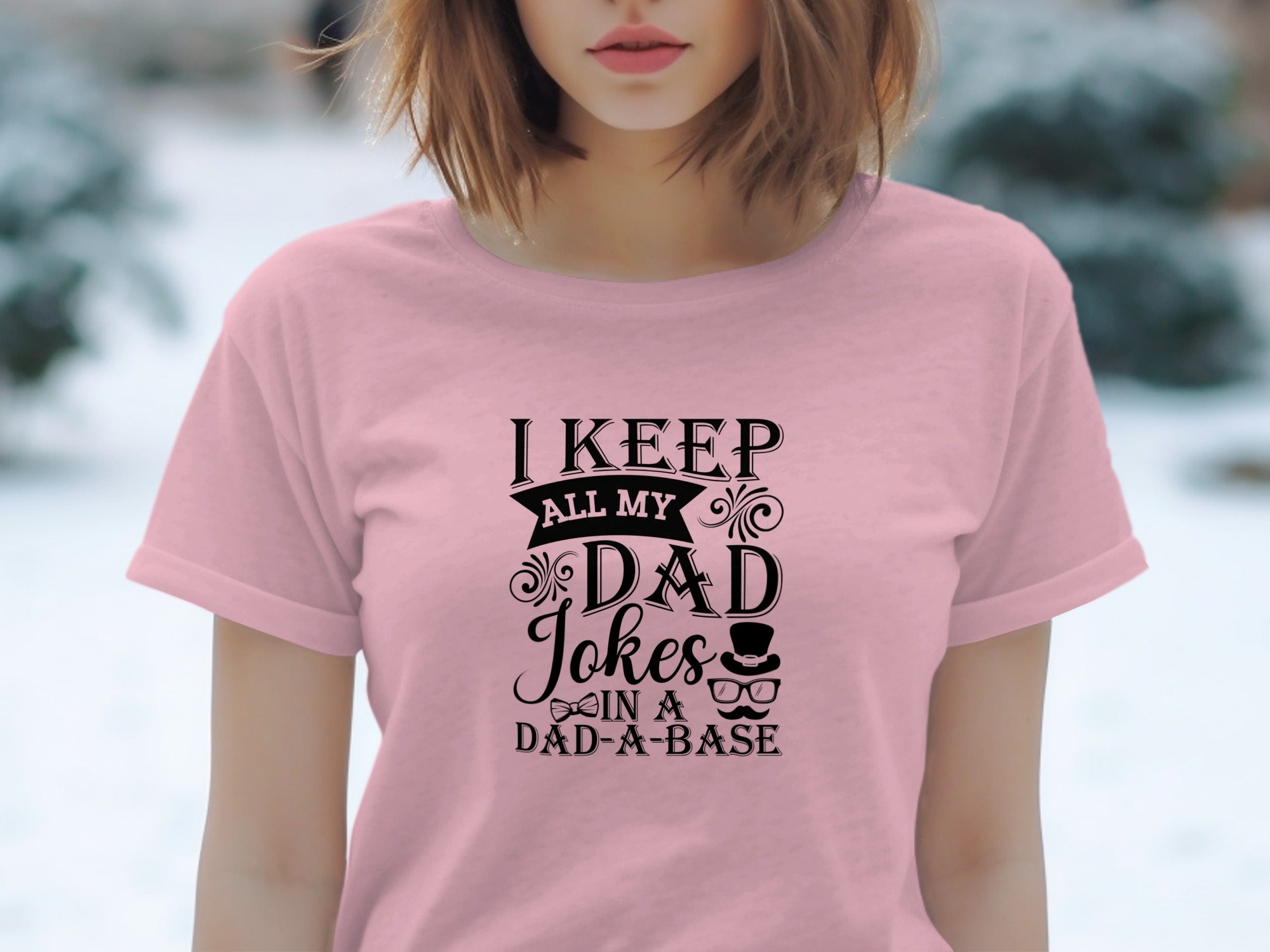 Pink t-shirt with black text: "I KEEP ALL MY DAD Jokes IN A DAD-A-BASE".