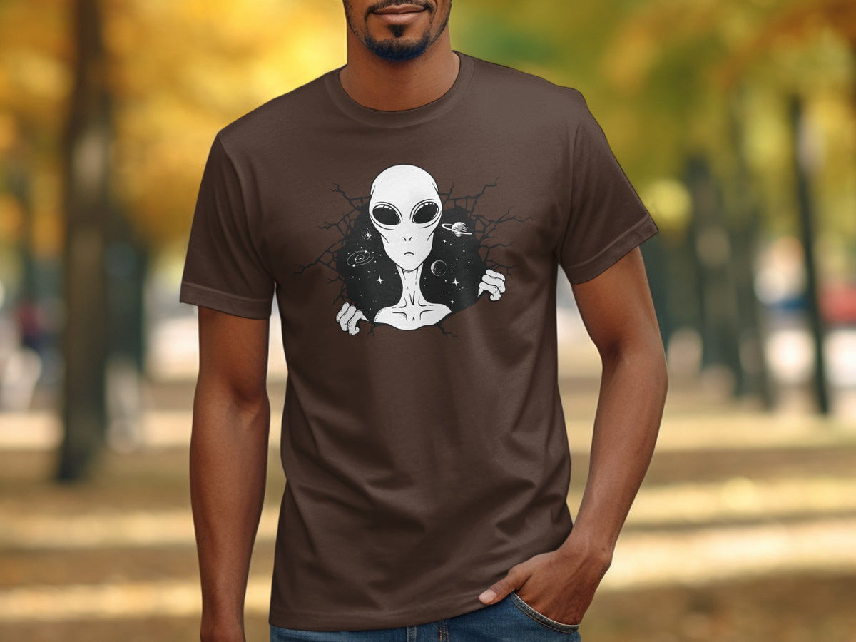Brown t-shirt with a graphic of a gray alien breaking through a starry background.