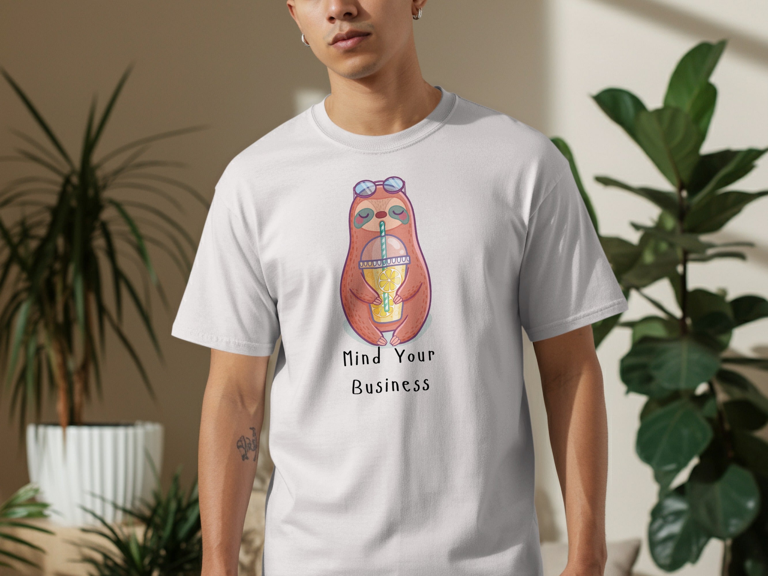 White t-shirt with cartoon sloth holding drink, text "Mind Your Business".