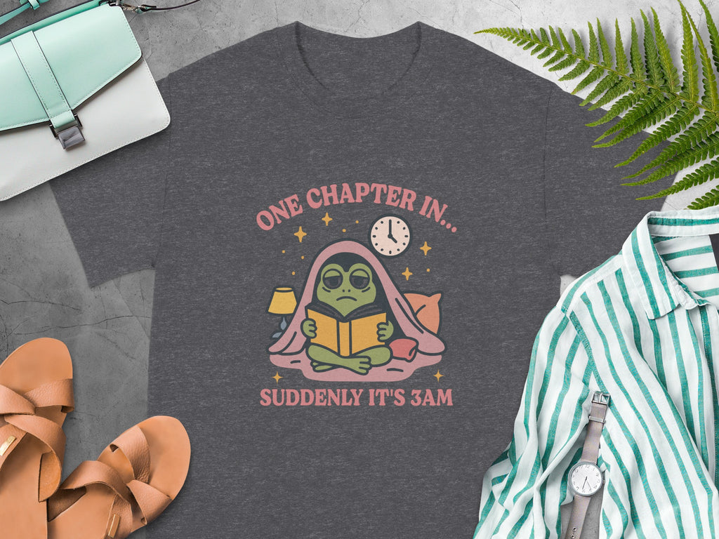 Dark gray t-shirt with frog reading under blanket and text "ONE CHAPTER IN... SUDDENLY IT'S 3AM".