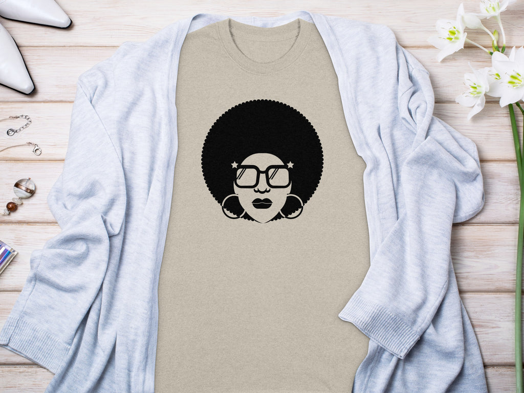 Tan t-shirt with a black graphic of a woman with an afro and star-shaped glasses.