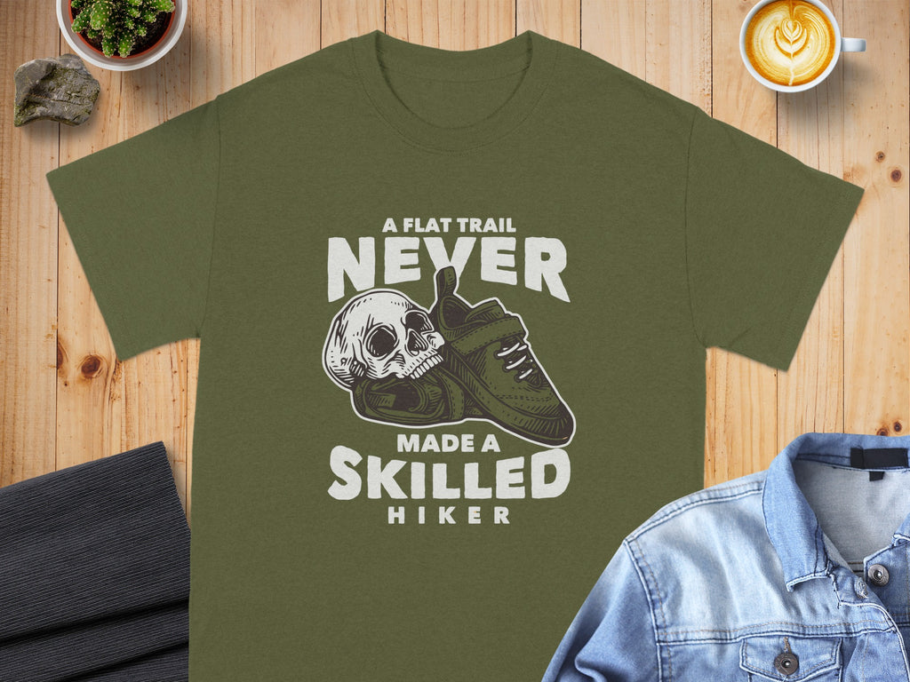 Olive green t-shirt with skull, boot, and text "A Flat Trail Never Made a Skilled Hiker" graphic.