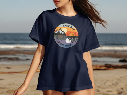 Navy t-shirt with circular graphic of mountains, campfire, and tent contrasting day and night scenes.