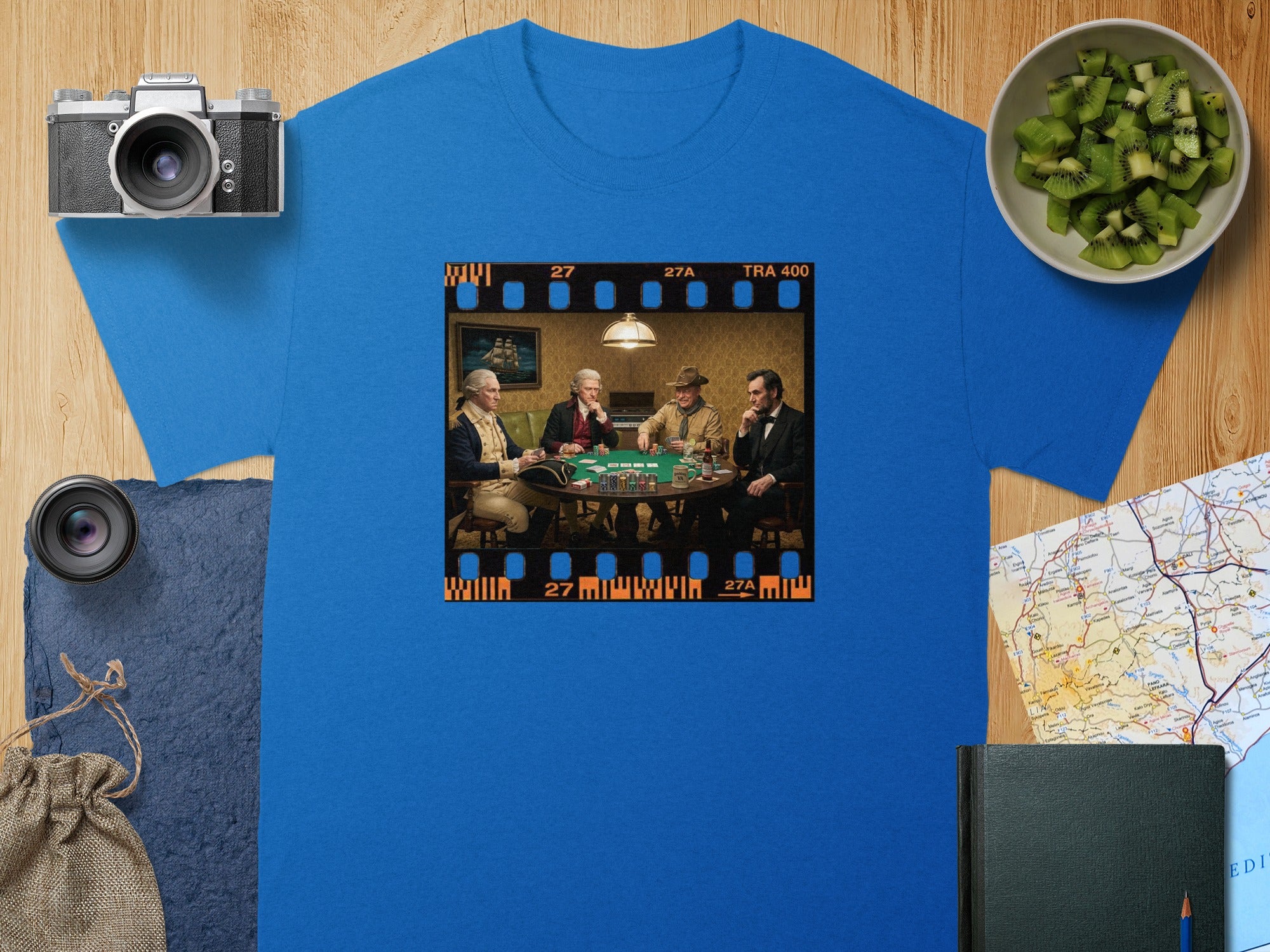 Four historical figures play a poker game in a film strip on a blue t-shirt.