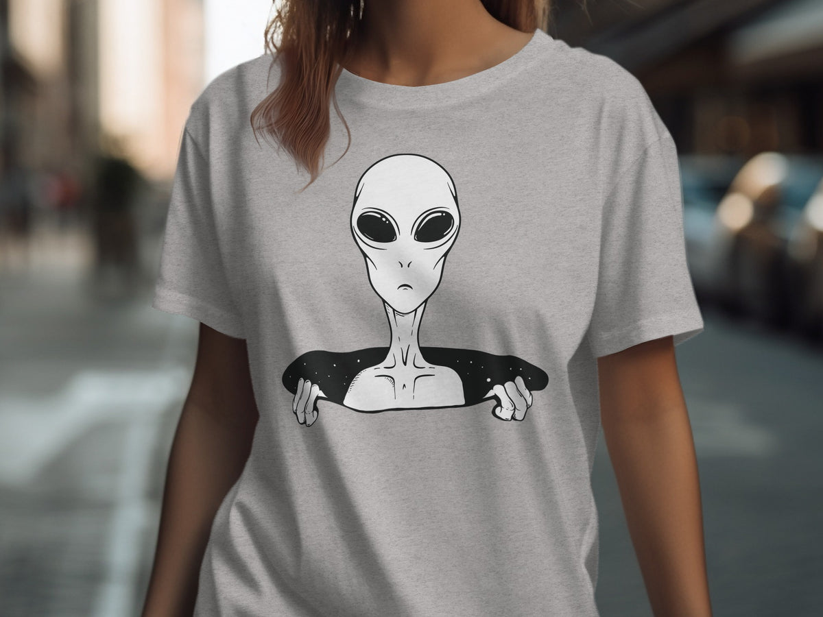 Gray t-shirt with a black and white alien illustration peeking through a starry hole.