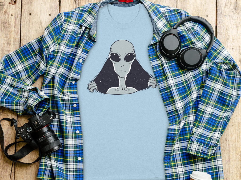 Light blue t-shirt with alien graphic, plaid shirt, headphones, and camera.