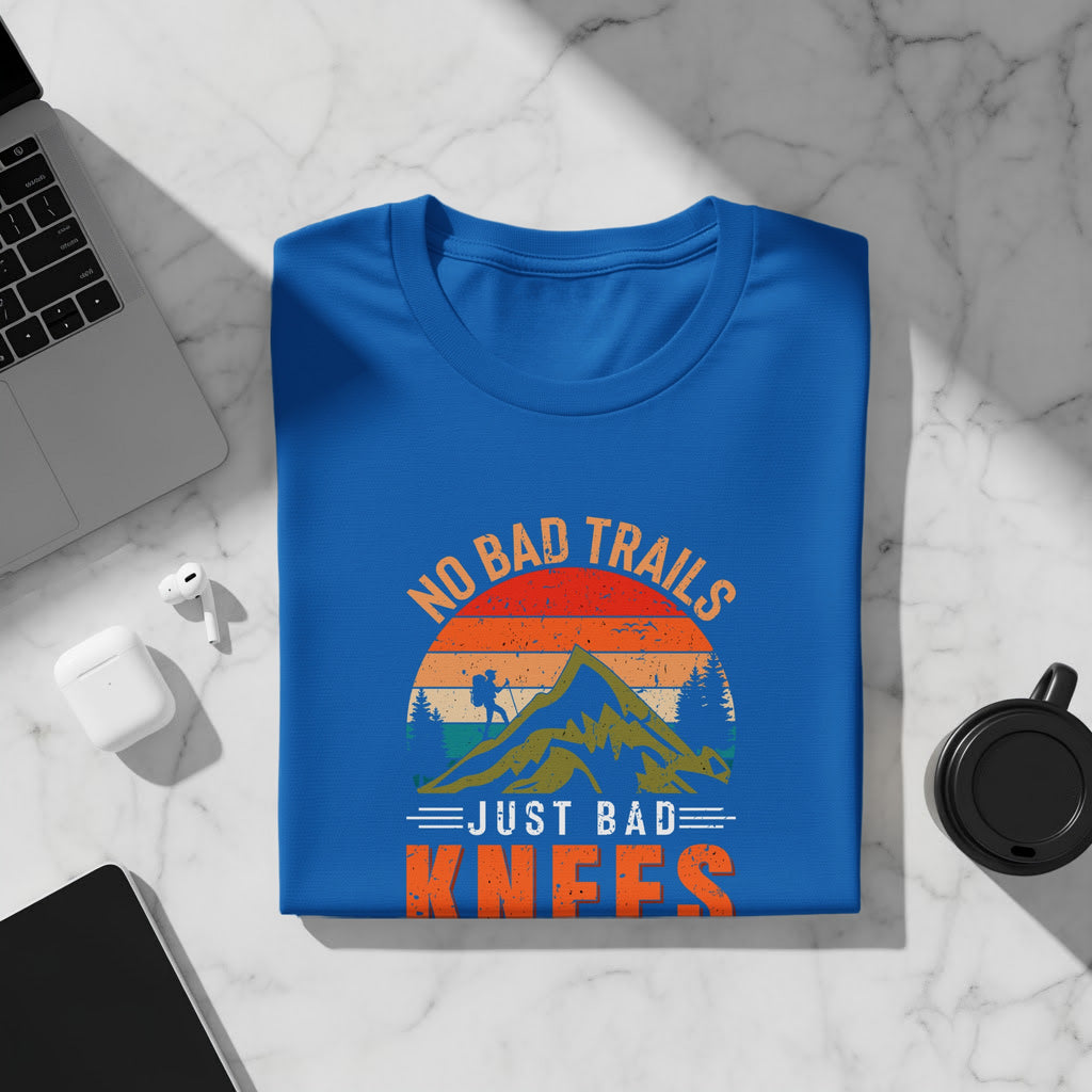 Blue t-shirt with "NO BAD TRAILS JUST BAD KNEES" graphic featuring a hiker and mountains.