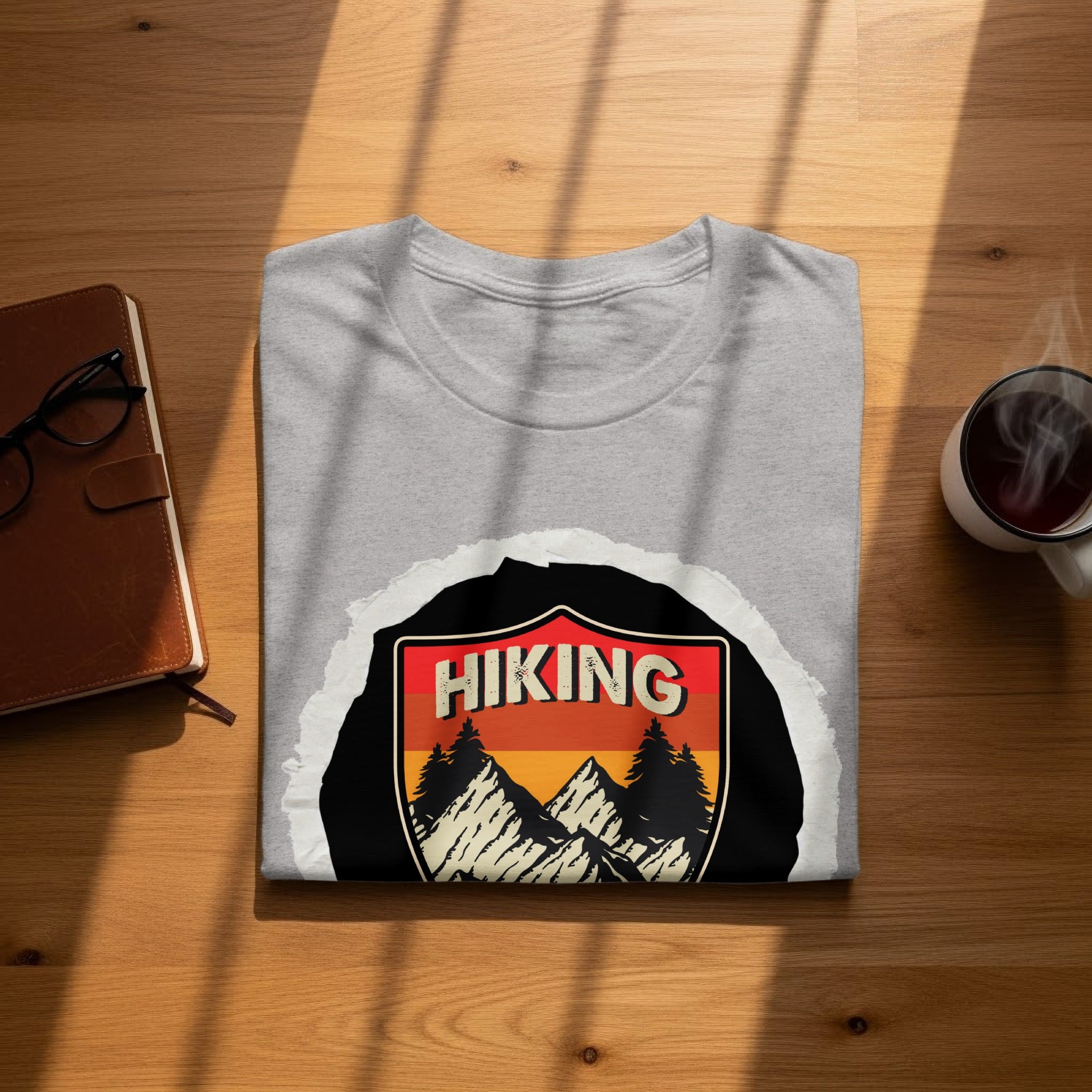 Gray t-shirt with a shield design featuring mountains, pine trees, and the text "HIKING".