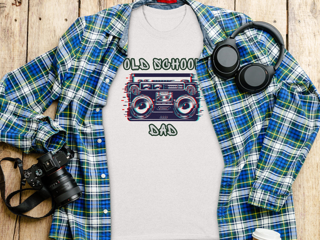 T-shirt with "Old School Dad" text and graphic of a boombox, laid flat with a plaid shirt and headphones.