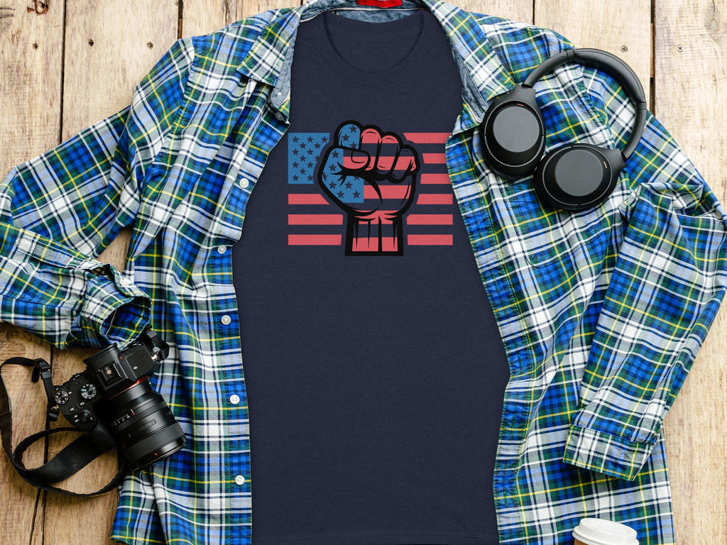Navy graphic tee with American flag fist and plaid shirt layed open.