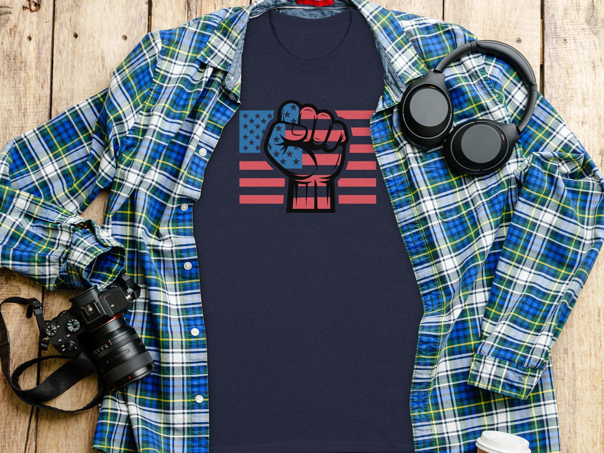 Navy graphic tee with American flag fist and plaid shirt layed open.