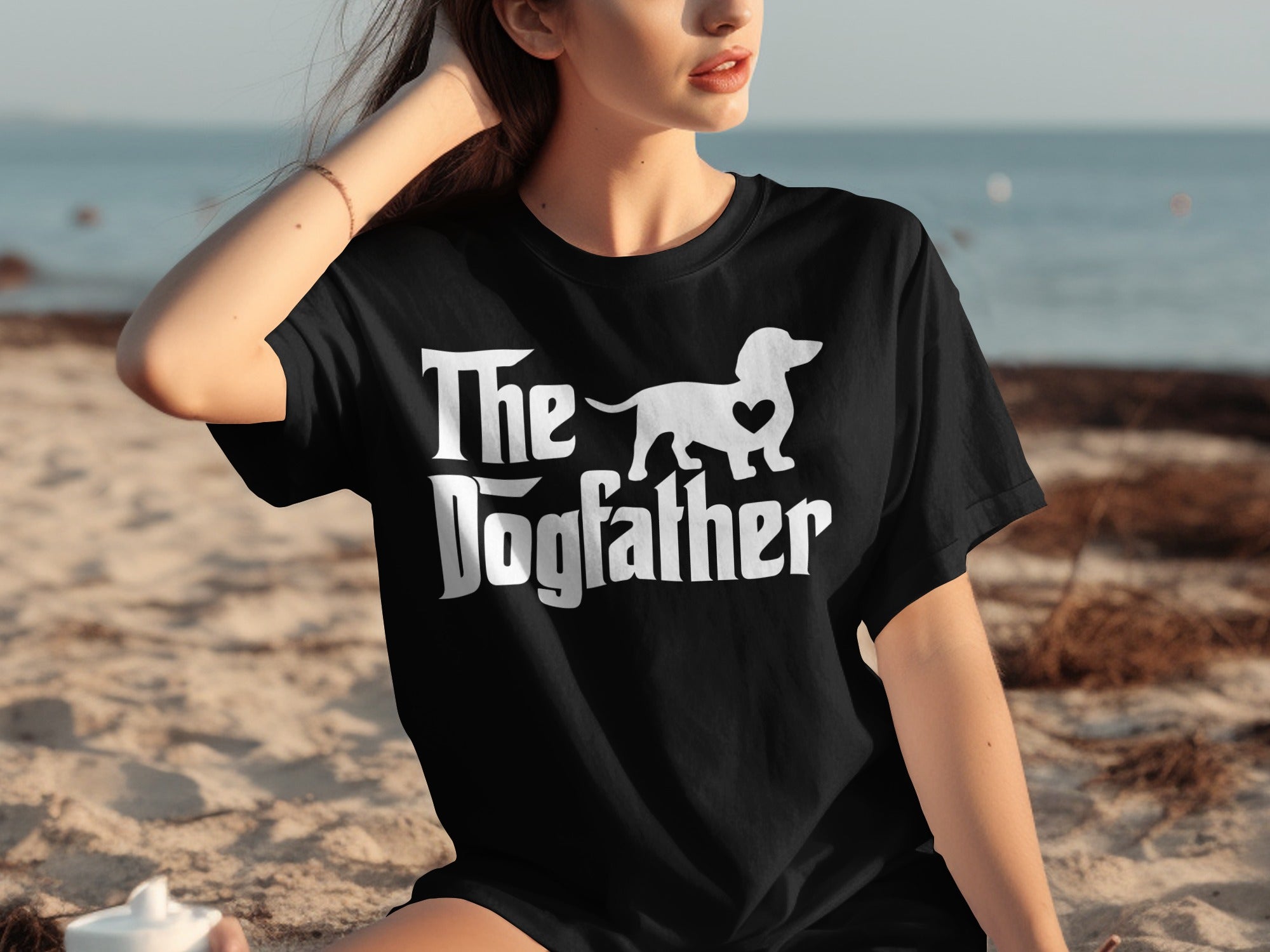 Black t-shirt with white text "The Dogfather" and a dachshund silhouette with a heart.