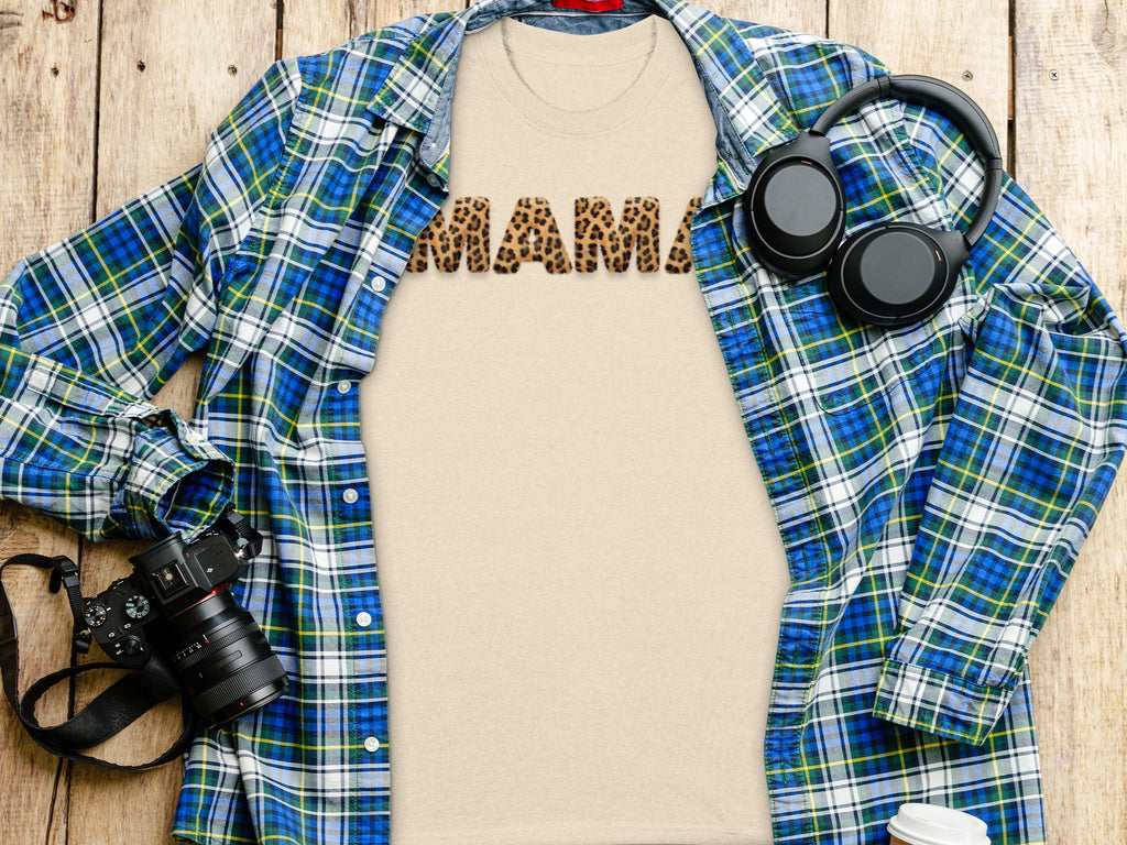 Beige t-shirt with "MAMA" in leopard print letters, open plaid shirt, headphones, and camera.