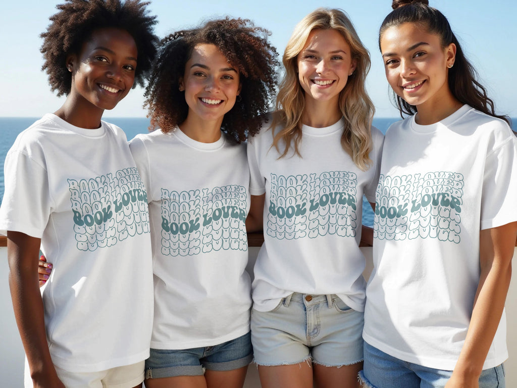 Four smiling women in white t-shirts with "BOOK LOVER" text in bubble letters.