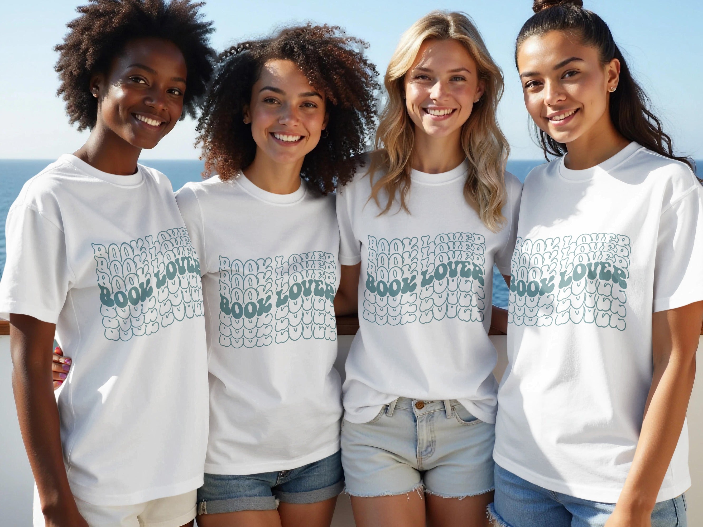 Four smiling women in white t-shirts with "BOOK LOVER" text in bubble letters.