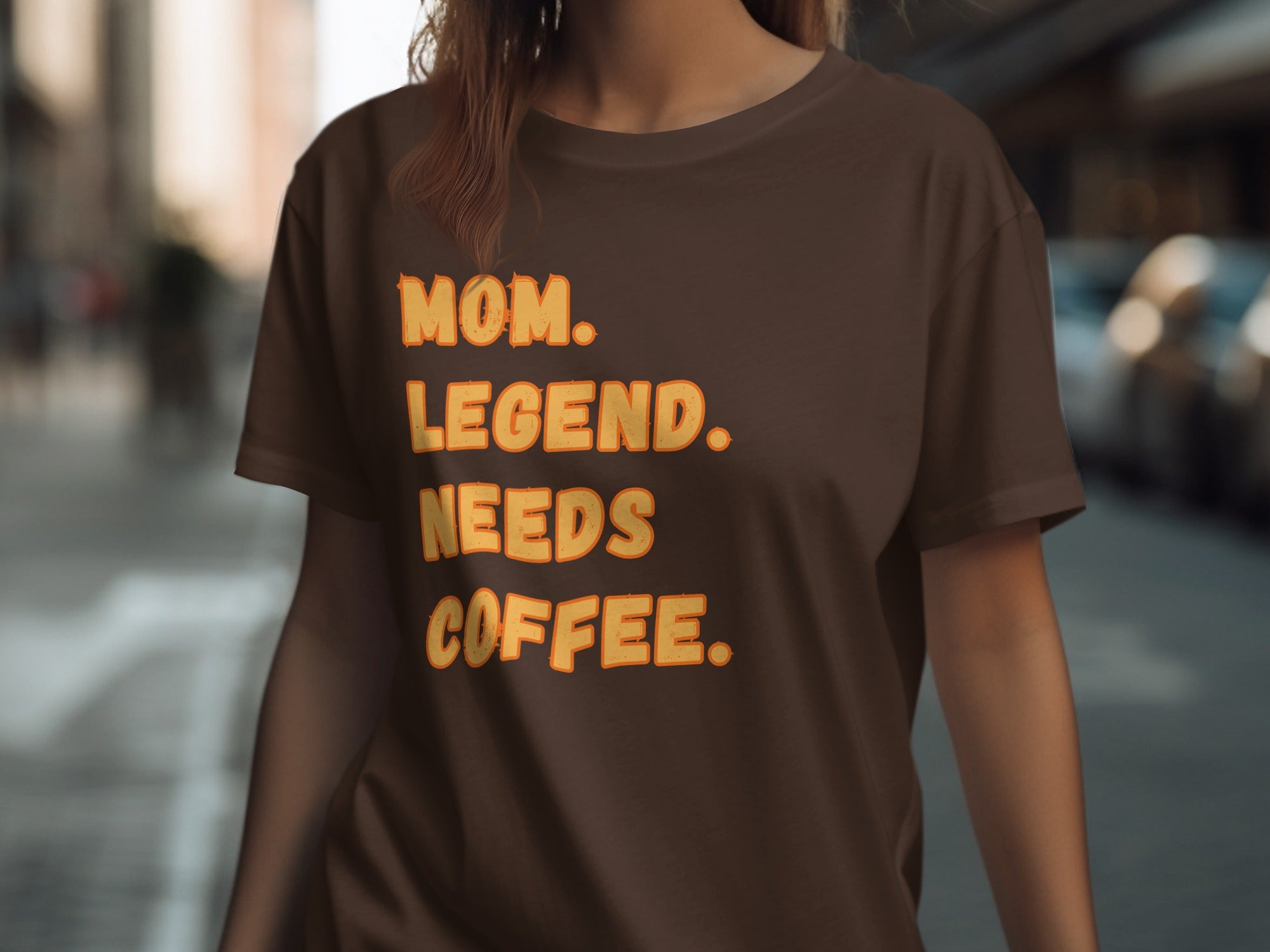 Brown t-shirt with orange text reading "MOM. LEGEND. NEEDS COFFEE."