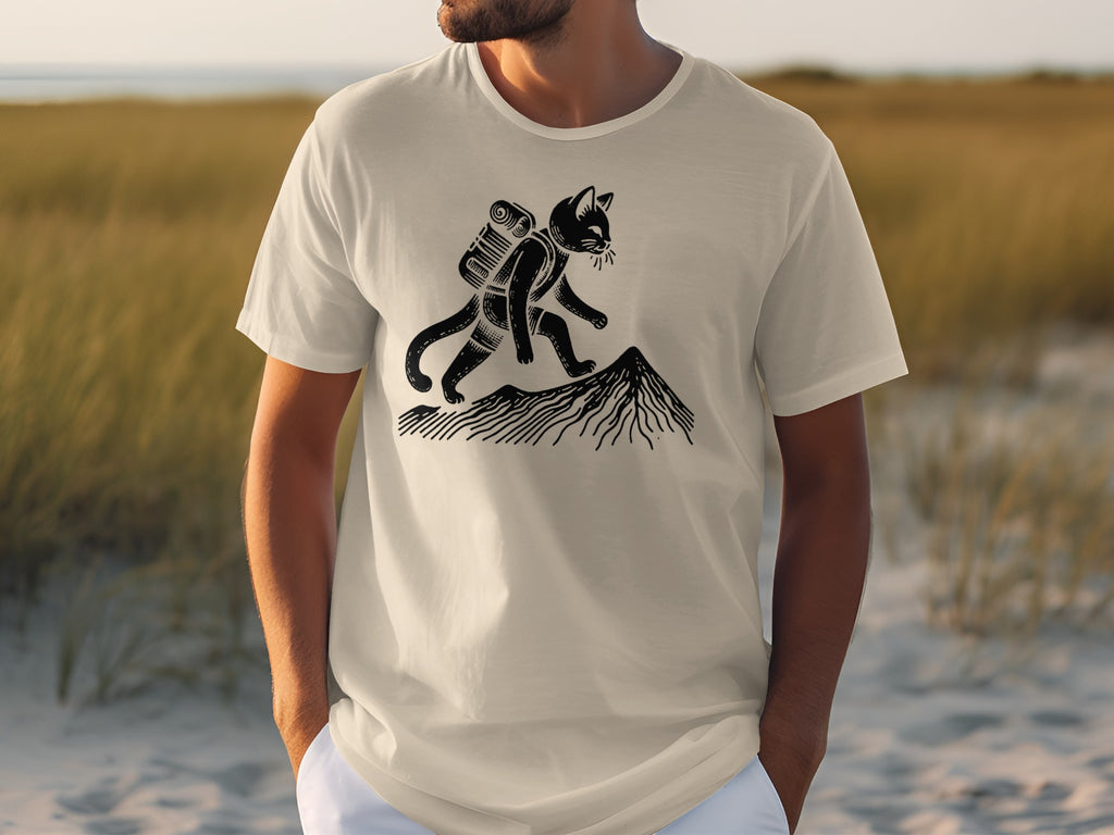 T-shirt featuring a black cat with a backpack hiking up a mountain.