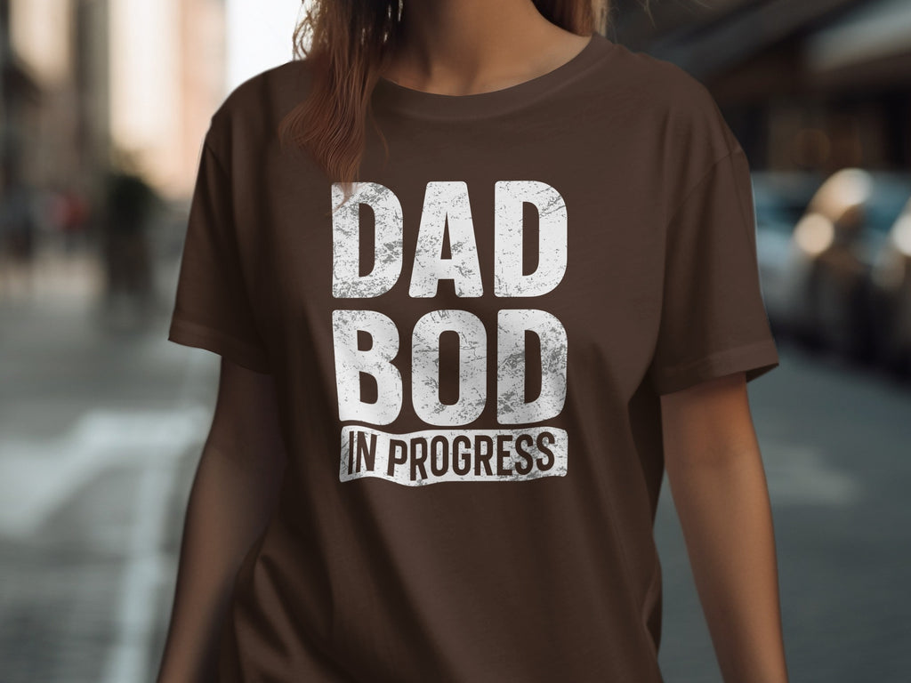 Brown t-shirt with white distressed text that reads "DAD BOD IN PROGRESS".
