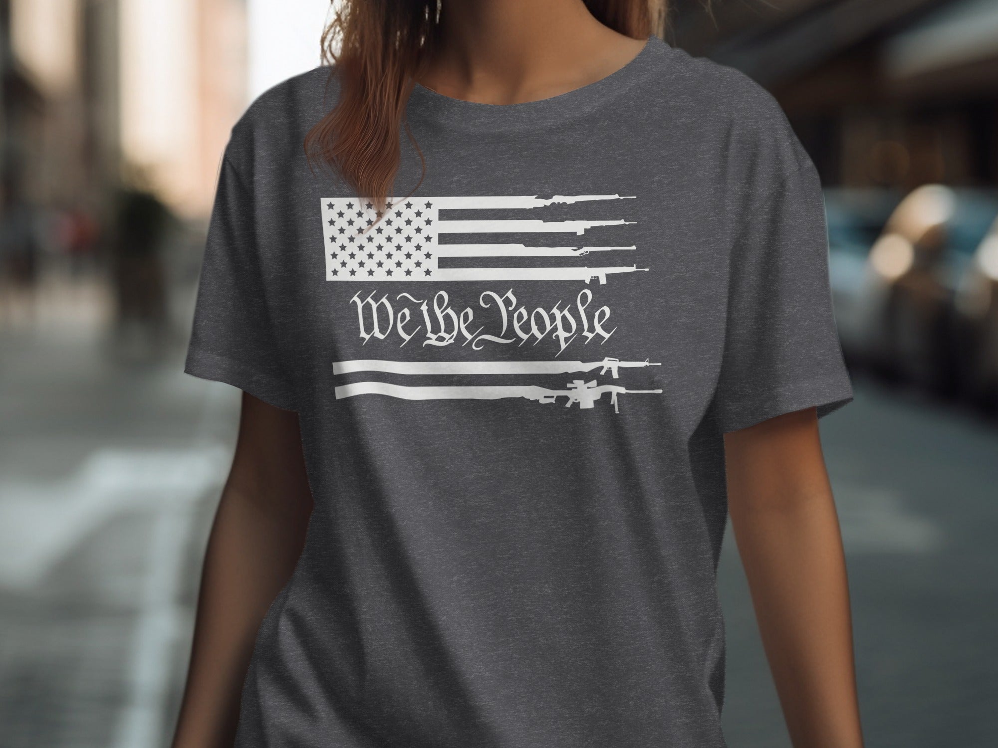 Dark grey t-shirt with white American flag design featuring firearms and the text "We the People".