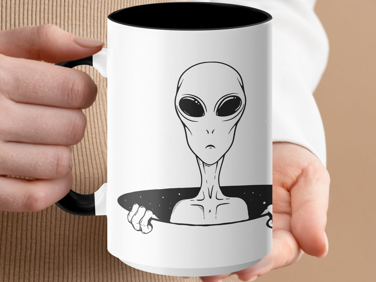 White mug with black interior and handle, featuring a black and white alien illustration.