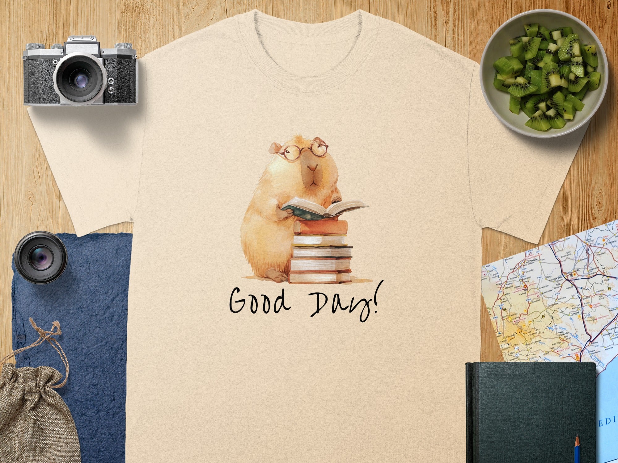 Capybara wearing glasses reads a book on a stack of books with "Good Day!" text.
